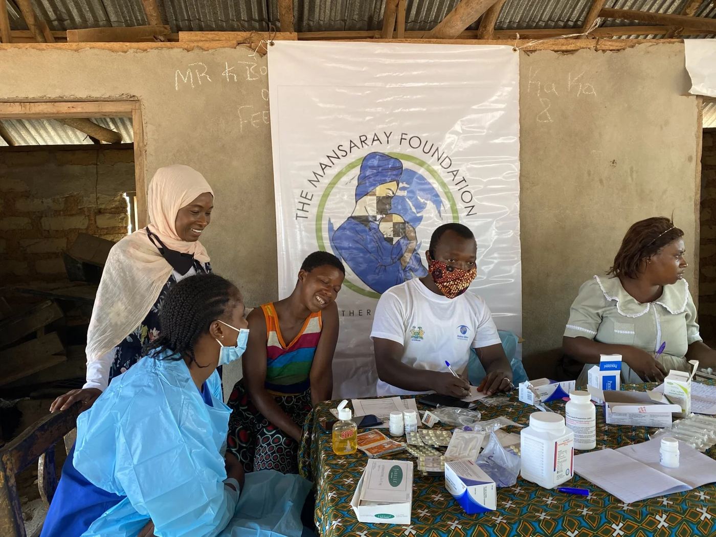 Health workers seeing women at an outreach session beneath a Mansaray Foundation banner
