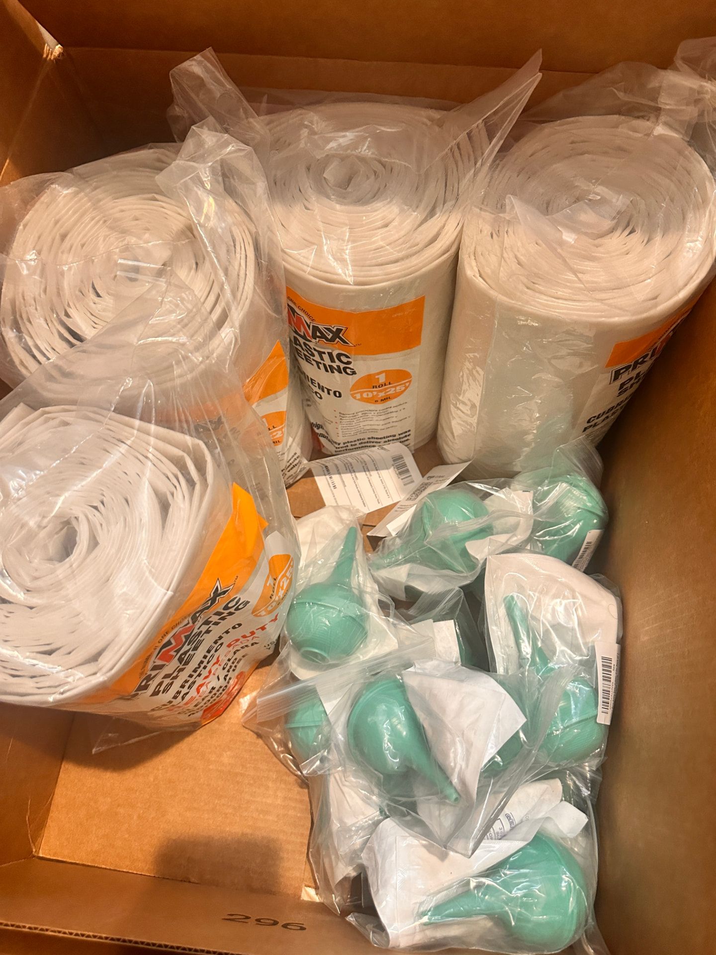 Rolled plastic sheeting and green bulb syringes packed in a box