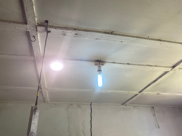 Newly installed lights glowing on a white-painted ceiling inside a facility room