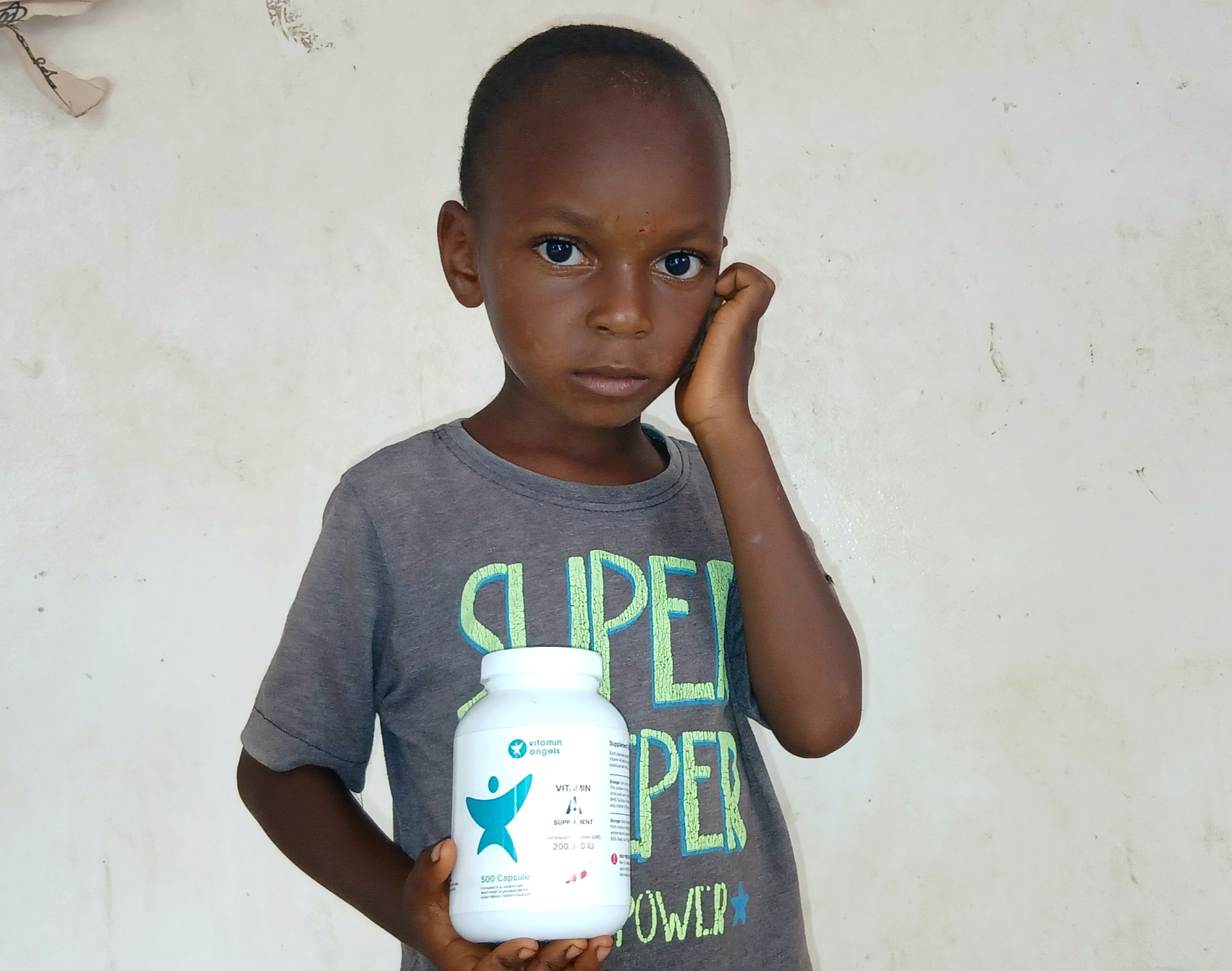 A young child holding a Vitamin Angels bottle