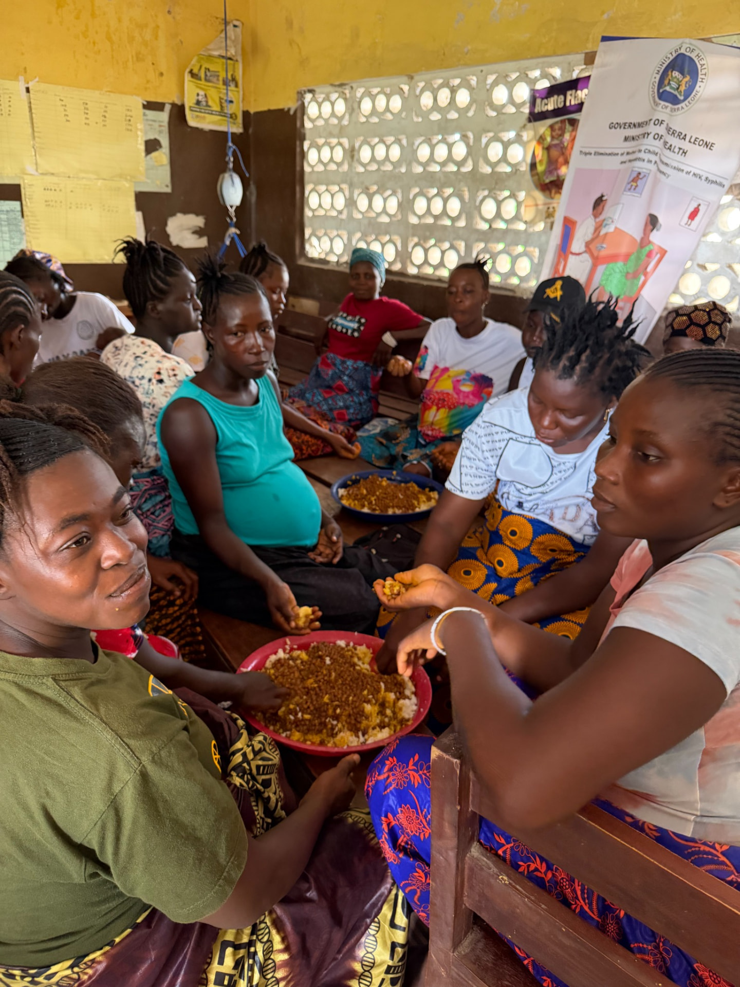 Women eating together from shared bowls inside a health facility