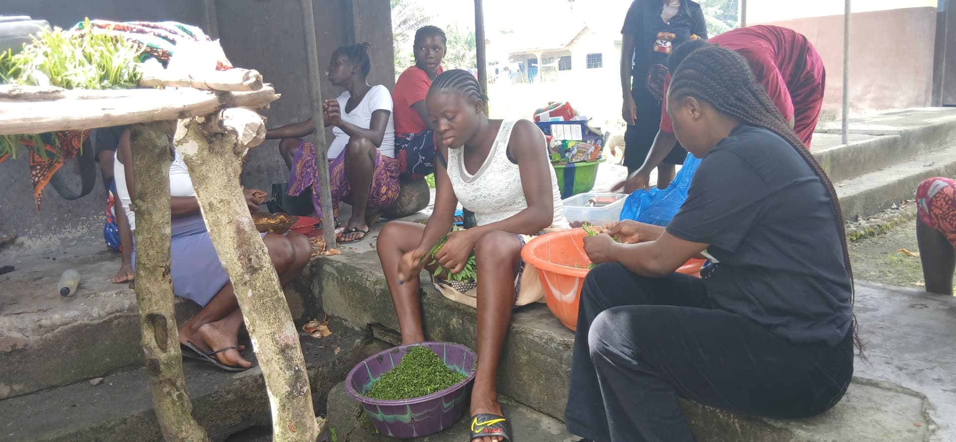 Women and TMF team members preparing vegetables and food together