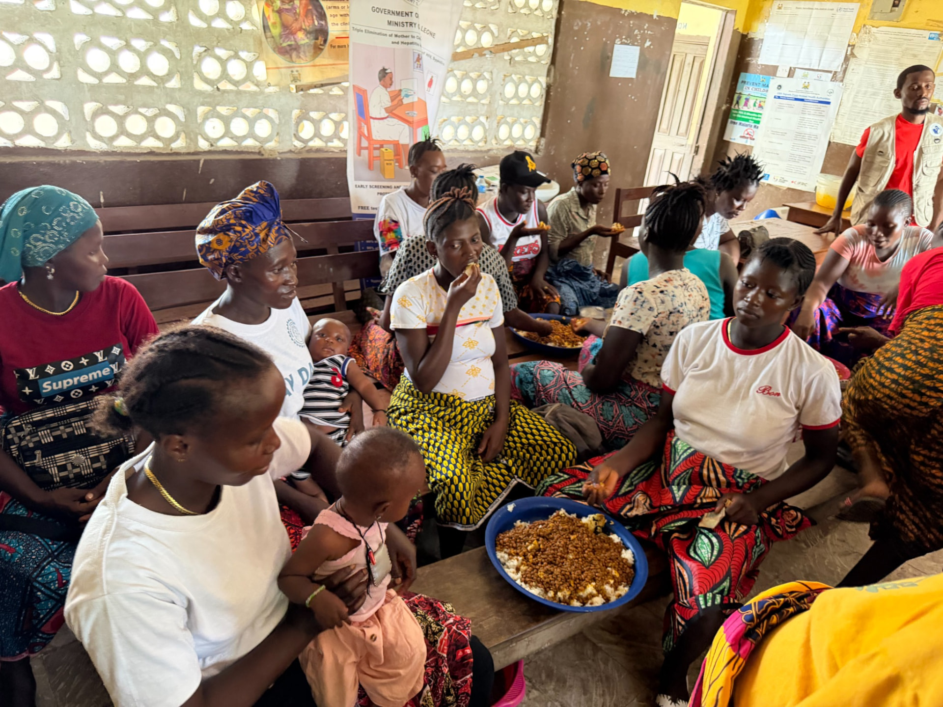 Women and young children sharing a meal together inside a clinic waiting area